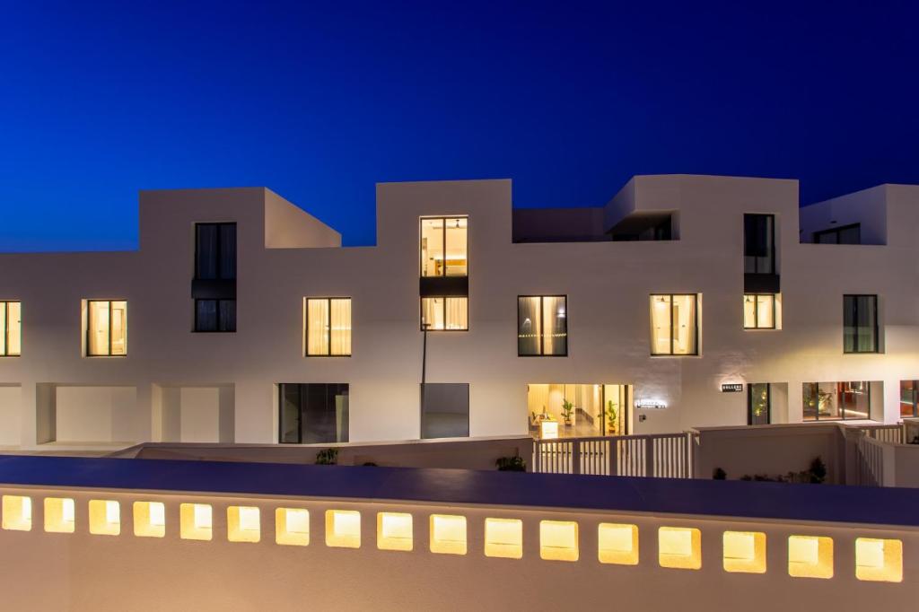 un edificio blanco con ventanas iluminadas por la noche en Hotel Apartamentos Hamus en Conil de la Frontera