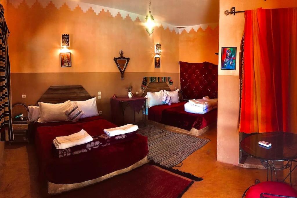a bedroom with two beds and a table and a room at La Kasbah du Jardin in Aït Benhaddou