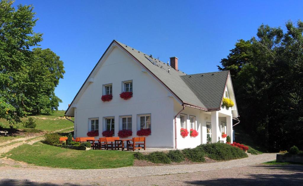a white house with flowers on the windows at Selský dvůr 1 in Police nad Metují