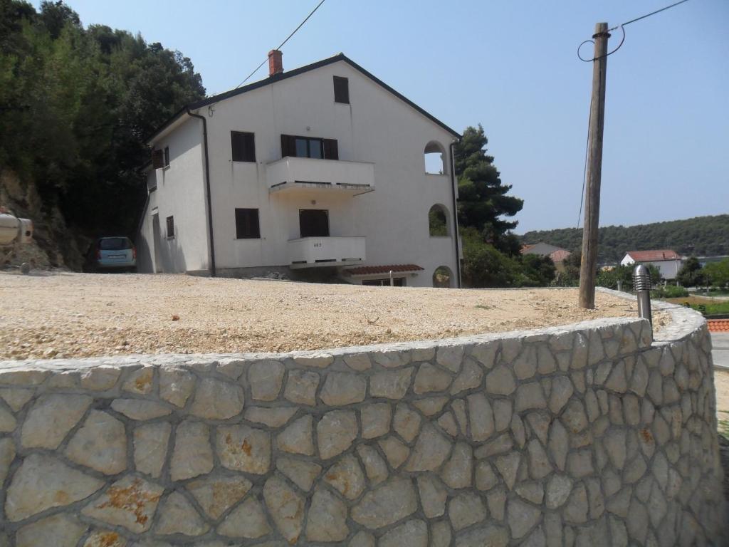 uma parede de pedra em frente a uma casa branca em Mar Eva Apartment em Rab