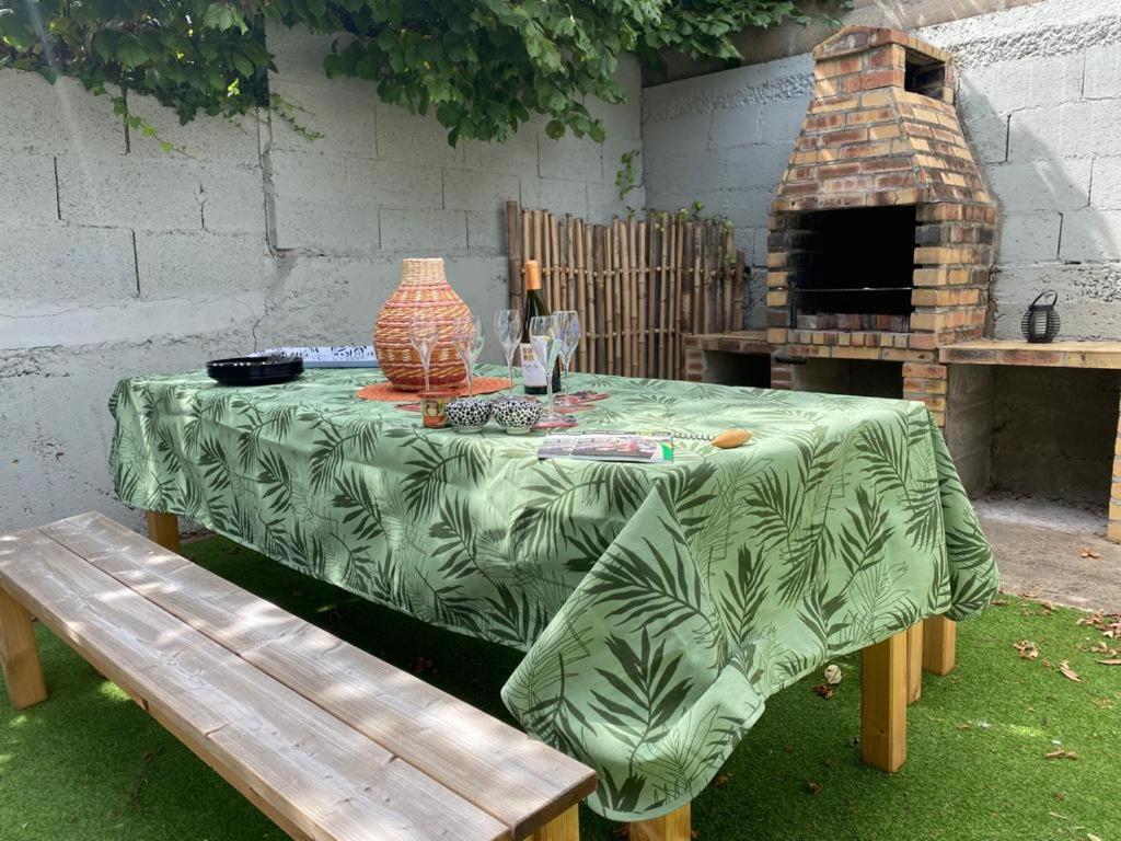 a table with a green tablecloth with a vase on top of it at Gite de la rivière avec patio et parking centre ville in Le Mans