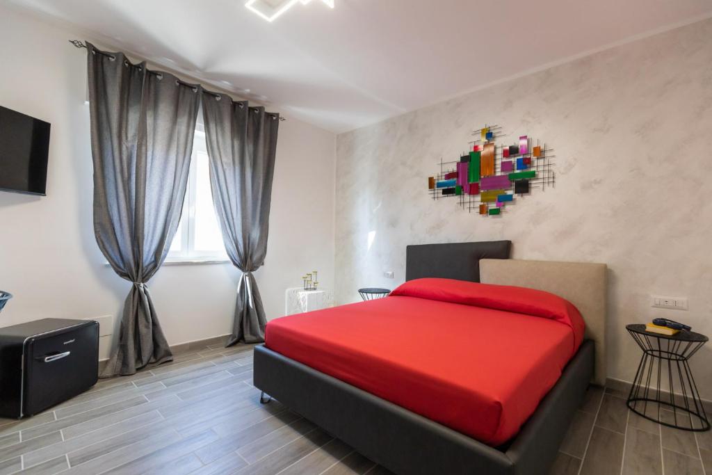 a bedroom with a red bed with a colorful painting on the wall at Residenza Saint Tropez in Santa Domenica