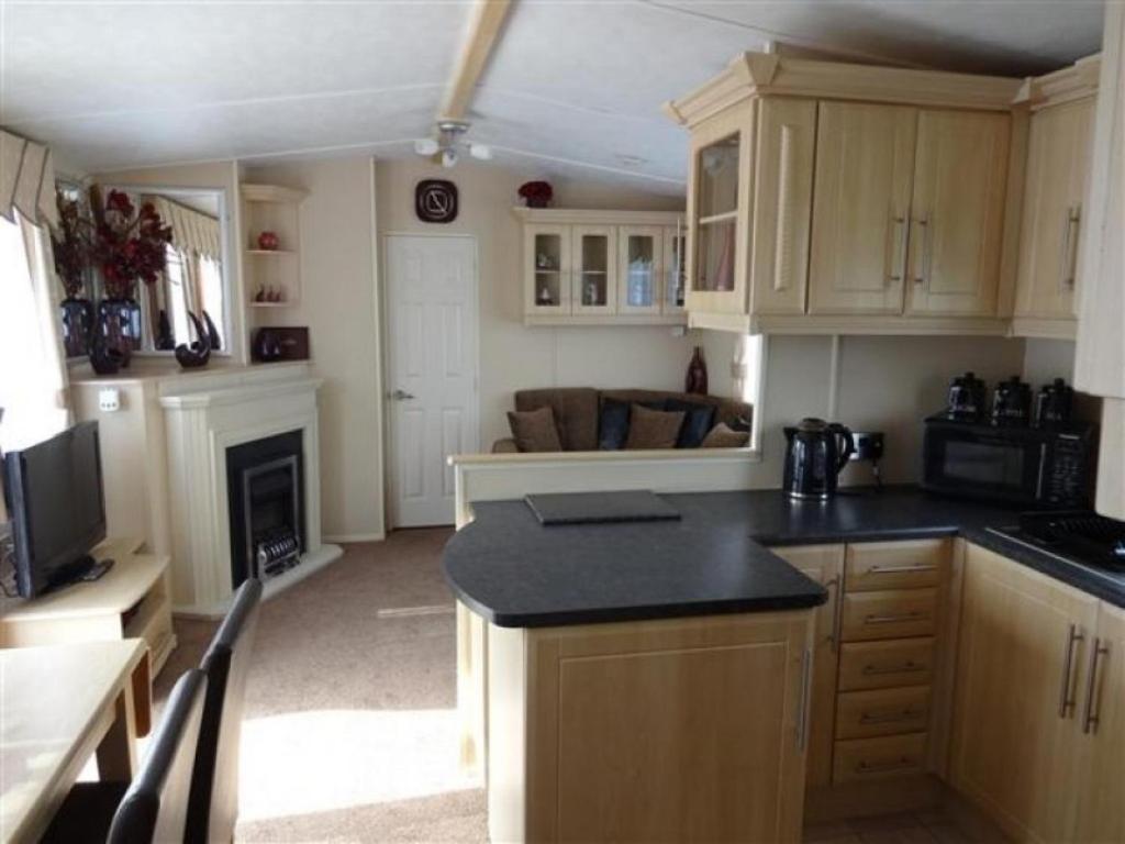 a kitchen with wooden cabinets and a stove top oven at Presthaven Sands in Prestatyn