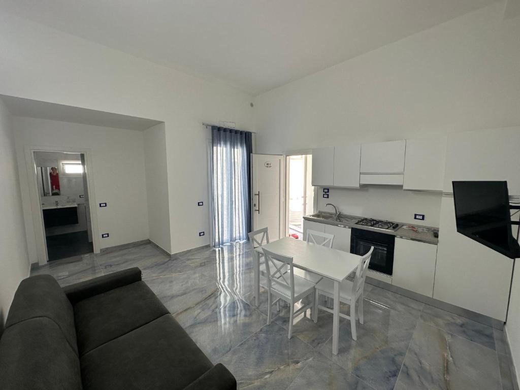 sala de estar con sofá, mesa y cocina en ALG Apartments con Parcheggio en Porto Cesareo