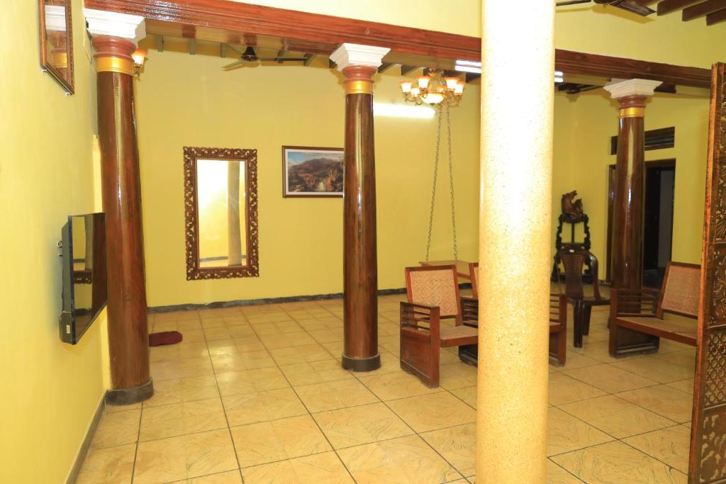 a room with columns and chairs and a mirror at Elite Heritage Stay in Puducherry