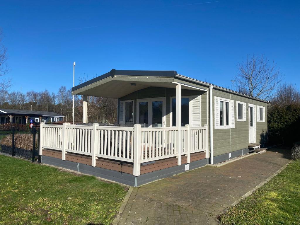 a mobile home with a porch and a white fence at Villetta Verde in Heusden