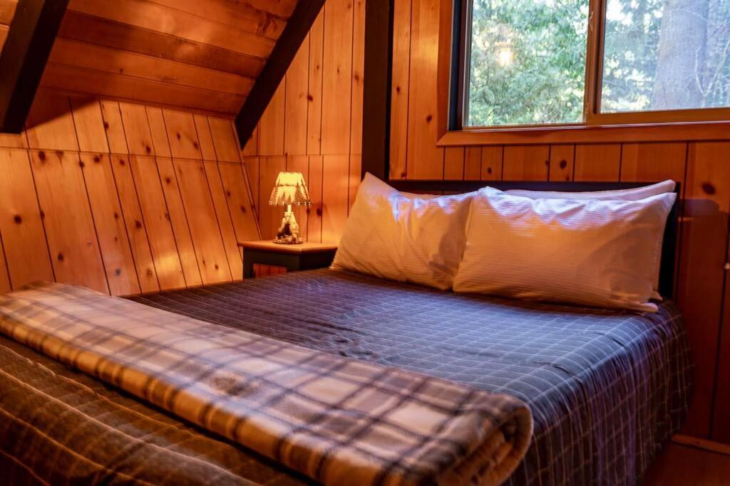 a bedroom with a bed in a wooden cabin at Retro A-Frame Cabin - Firepit & Fireplace in Skykomish