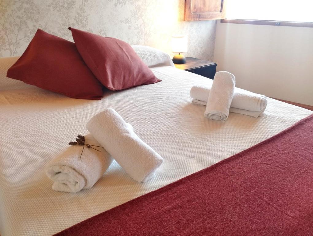 two towels on a white bed with pillows at Casa Aldea de Abaixo in Lugo