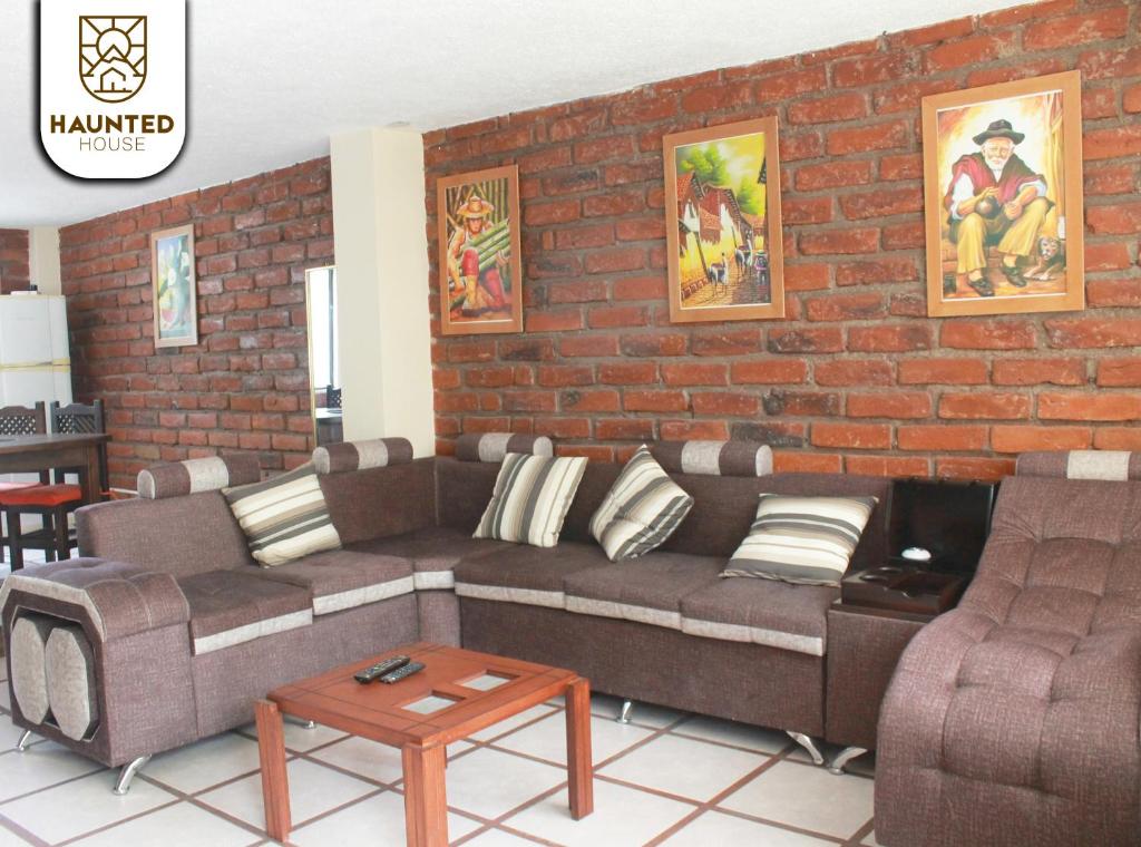 un soggiorno con divano e muro di mattoni di Haunted House Casa Vacacional a Baños