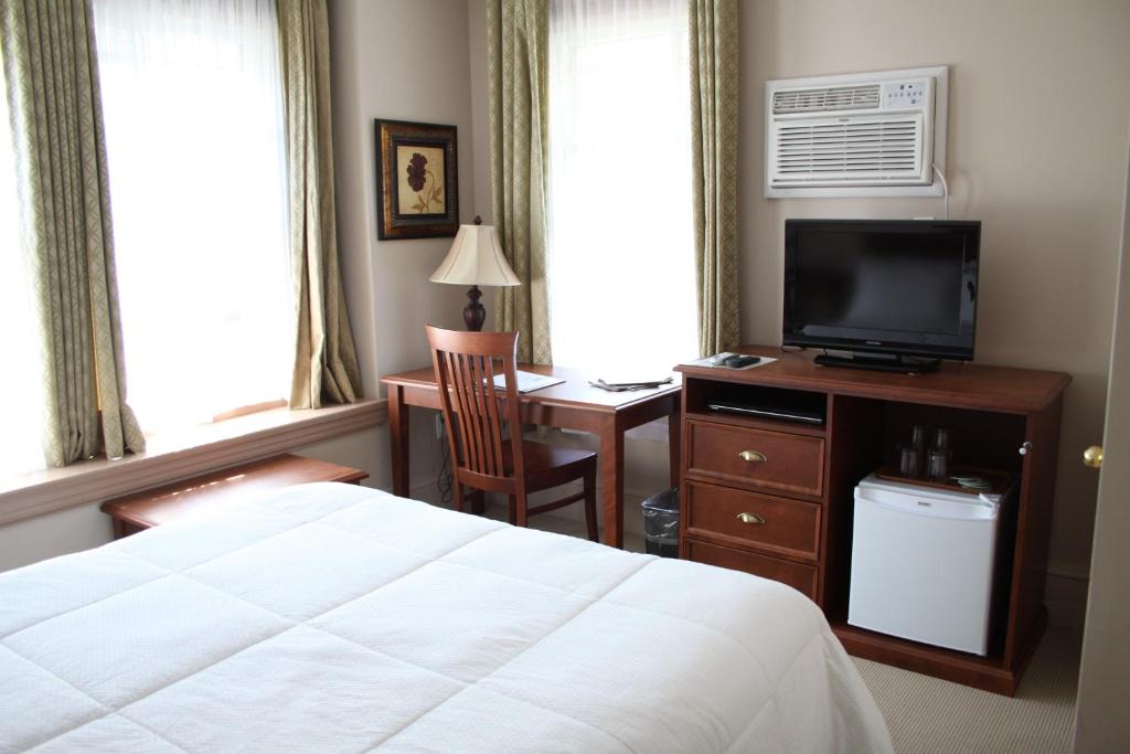 una camera con letto e scrivania con TV di The Sonata Inn a Charlottetown