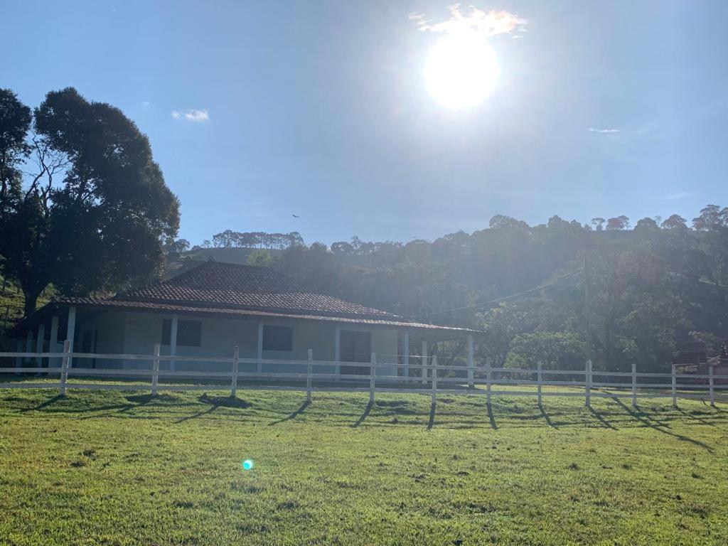 a house in a field with the sun behind it at Recanto Bellini's in Barreira