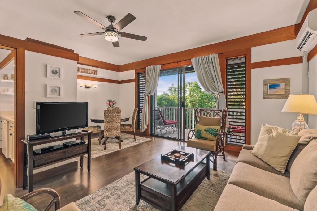 a living room with a couch and a tv at Kiahuna Plantation Renovated 1br, Private Lanai, AC 411 in Koloa