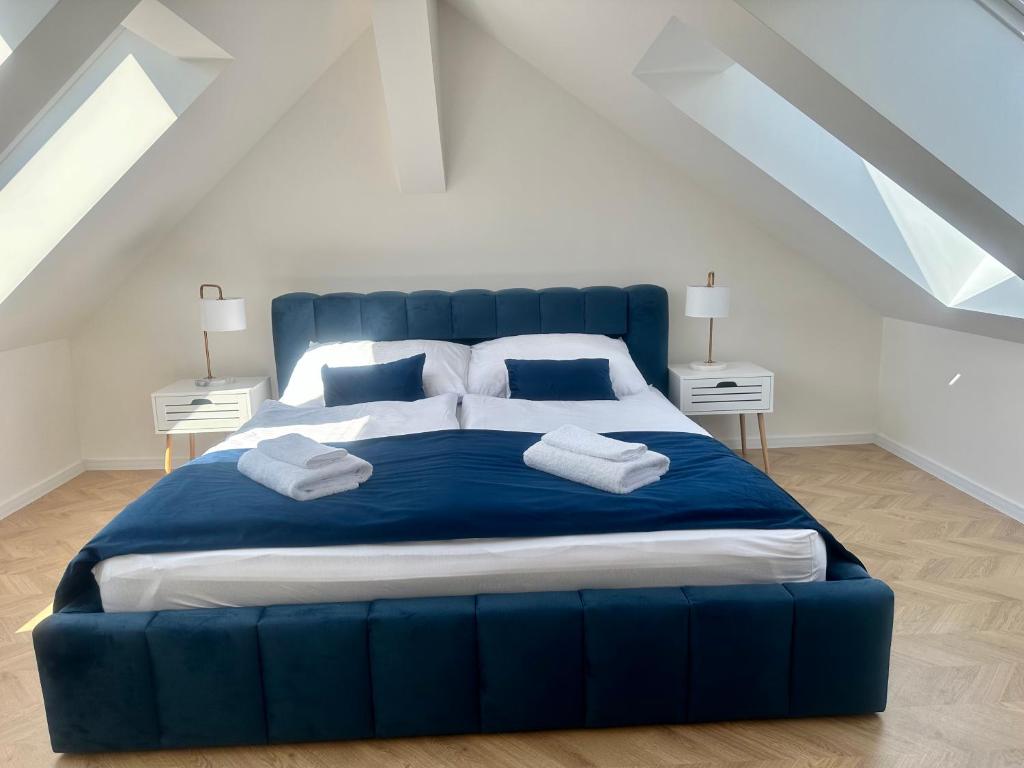 ein großes blaues Bett in einem weißen Zimmer mit 2 Tischen in der Unterkunft Apartmány Harmony Liptov in Liptovský Mikuláš