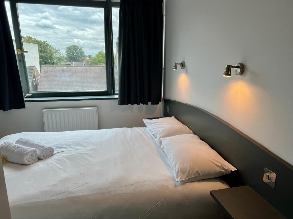 un letto con due cuscini, posto accanto a una finestra. di Hounslow Central Hotel a Hounslow