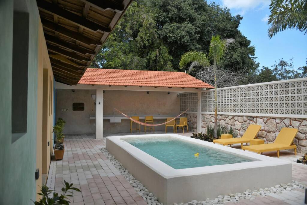 a backyard with a pool and a patio with yellow chairs at Trilliza-Verde in Campeche