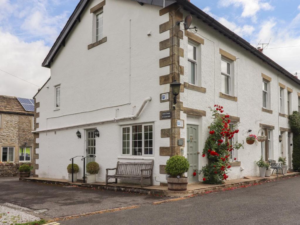 a white building with a bench in front of it at Dales Cottage in Grassington