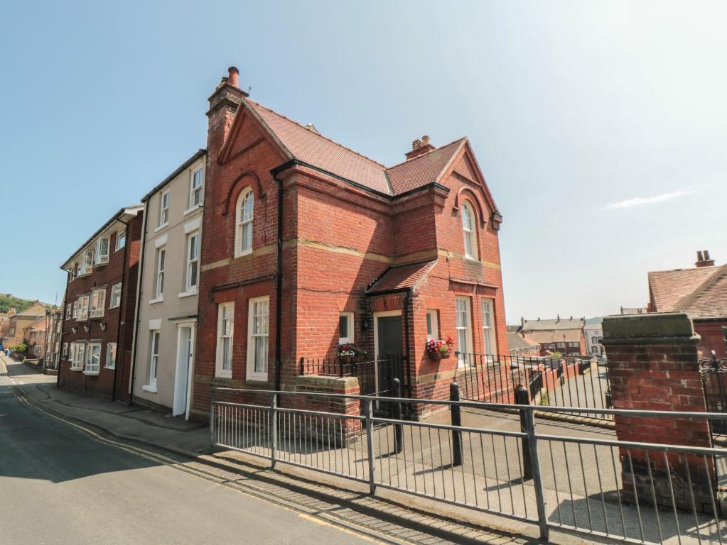 a brick building on a street with a fence at The Old School House in Scarborough