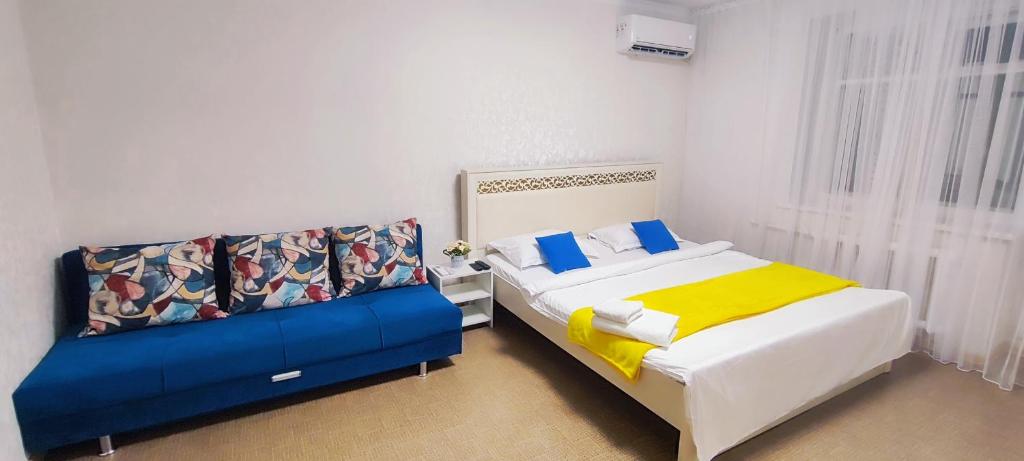 sypialnia z 2 łóżkami z niebieską i żółtą pościelą w obiekcie Апартаменты в центре города w mieście Aktobe