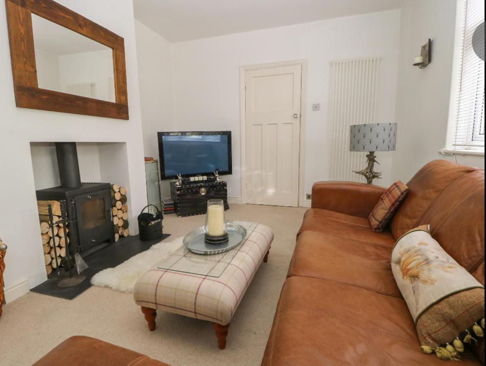 a living room with a brown couch and a television at Griff Lodge in Harome