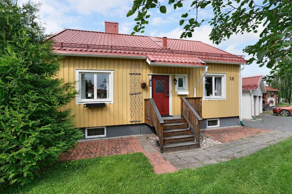 uma pequena casa amarela com uma porta vermelha em Guestly Homes - 5BR Corporate House em Boden