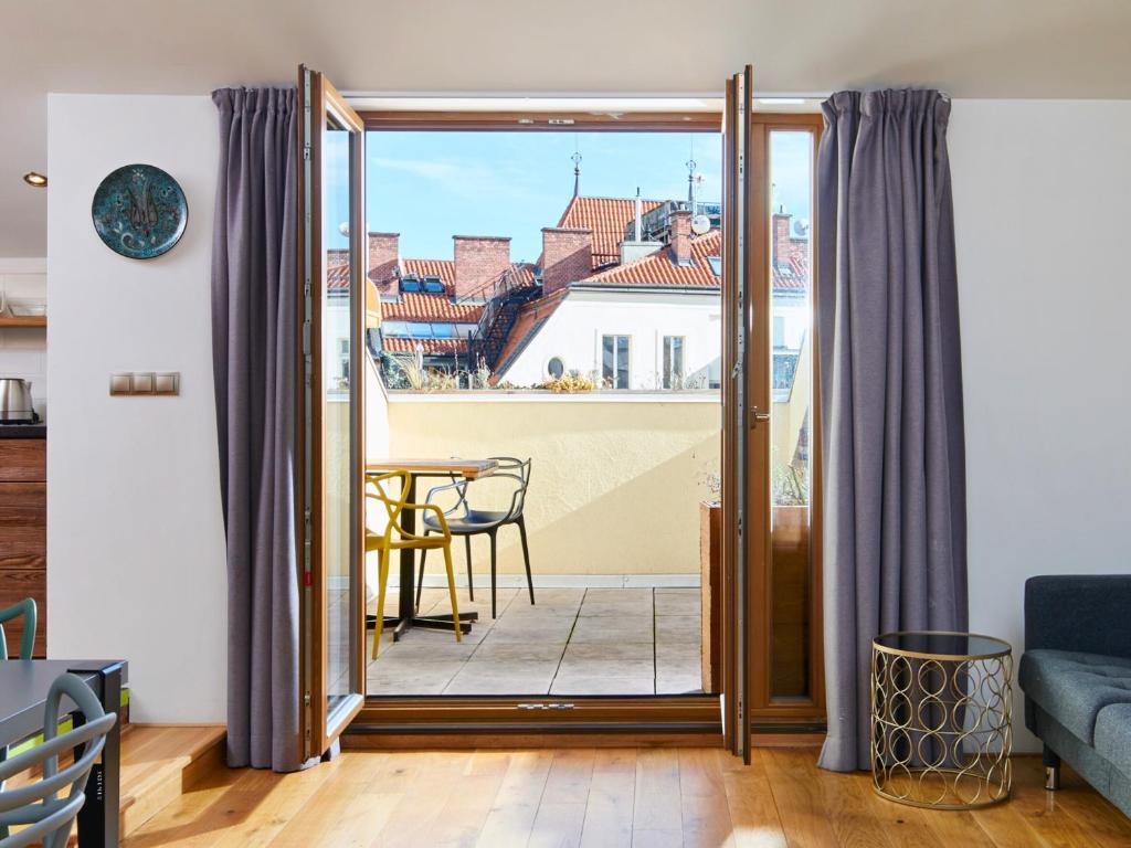Mordecai 12 Apartments by Adrez في براغ: غرفة معيشة مع باب مفتوح على شرفة مع طاولة