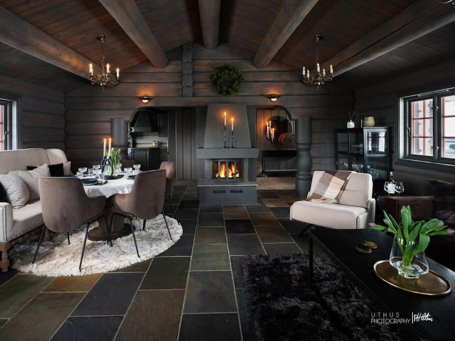uma sala de estar com uma mesa e uma lareira em Luxury log cabing, cross-country ski-in out, familiy getaway in great location em Geilo