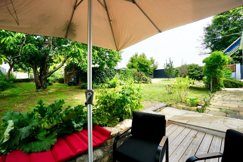 a patio with an umbrella and chairs on a deck at Logis Magnolia in Ploemeur