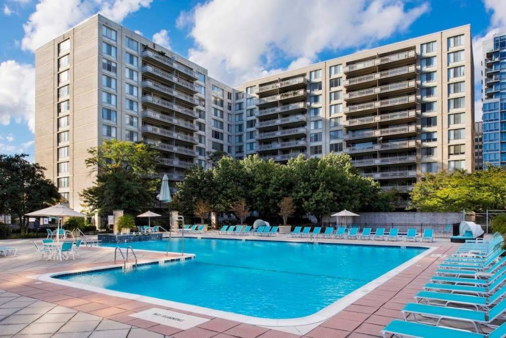 a large swimming pool with blue chairs and buildings at Luxury Condo in the heart of Crystal City in Arlington