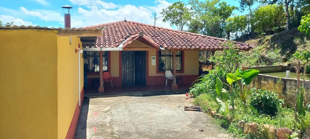 a small yellow house with a pathway leading to it at Finca Campestre Villa Carilina in Curití