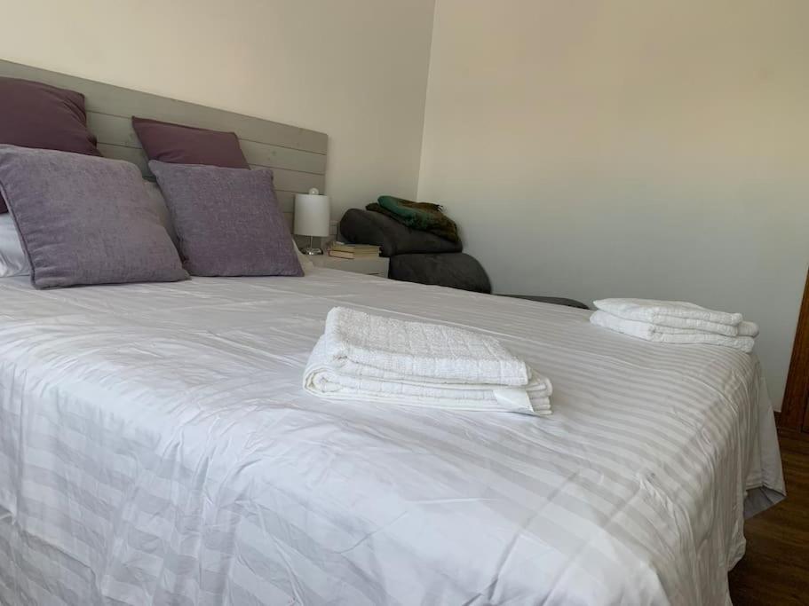 Una cama blanca con dos toallas encima. en Sueca 1, en Sueca