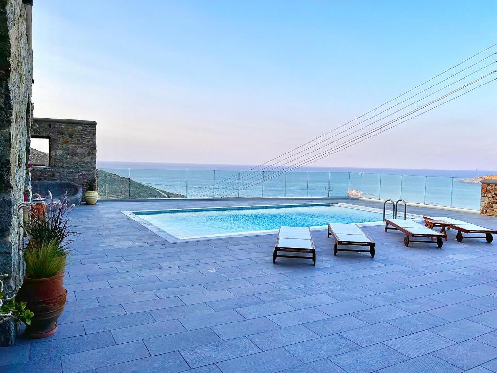 a swimming pool with benches and a view of the ocean at Villa Alba Mykonos in Agios Sostis Mykonos