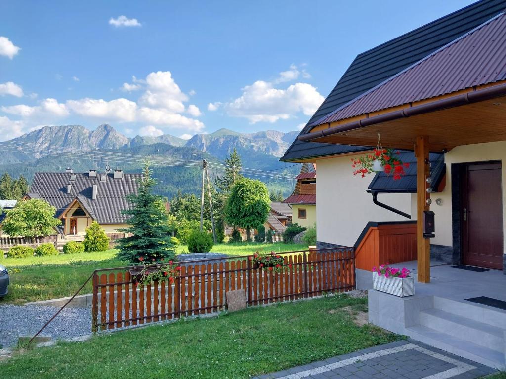 a house with a fence and mountains in the background at Apartament okno na Giewont in Kościelisko