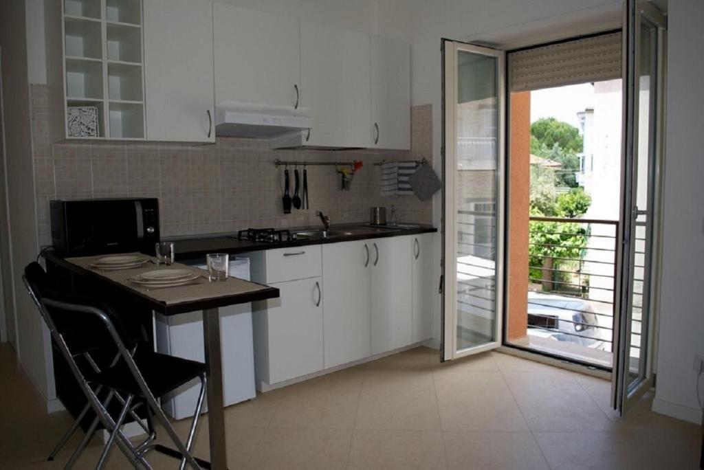 ヌマーナにあるBilo gianluca - nuovo appartamento in centro a Numanaのキッチン(白いキャビネット、テーブル、椅子付)