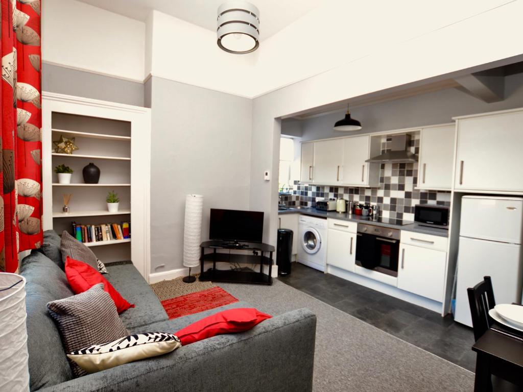 a living room with a couch and a kitchen at Stephen's Cheltenham apartment in Cheltenham