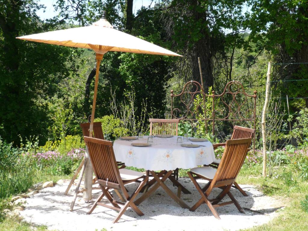 stół i krzesła pod parasolem w piasku w obiekcie Strohballenhaus Valle delle Rose w mieście Barchi