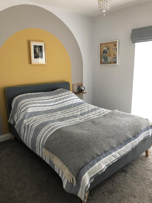 ein Schlafzimmer mit einem Bett mit einer gestreiften Decke in der Unterkunft Woodcliff in Birkenhead