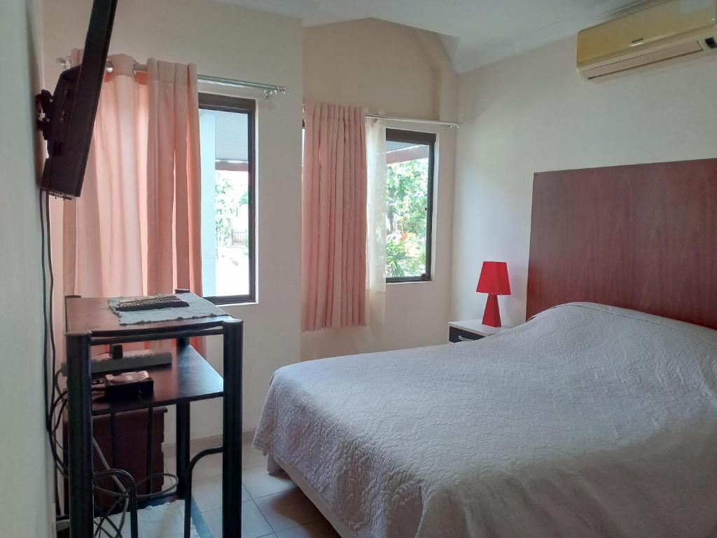 a bedroom with a bed and a desk and two windows at PEQUEÑO y ACOGEDOR DEPARTAMENTO CON GARAJE y recibe PEQUEÑOS PELUDITOS in Santa Cruz de la Sierra