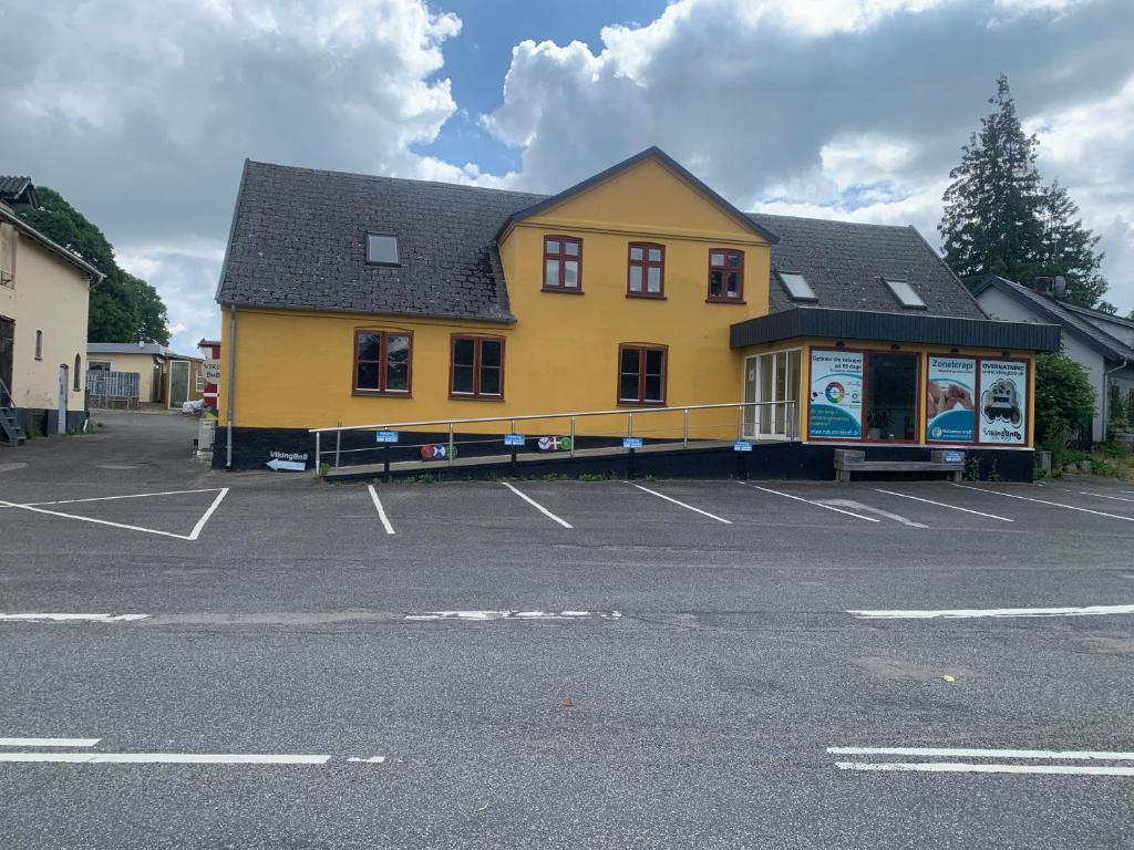 un gran edificio amarillo en un estacionamiento en VikingBnB en Kirke Såby