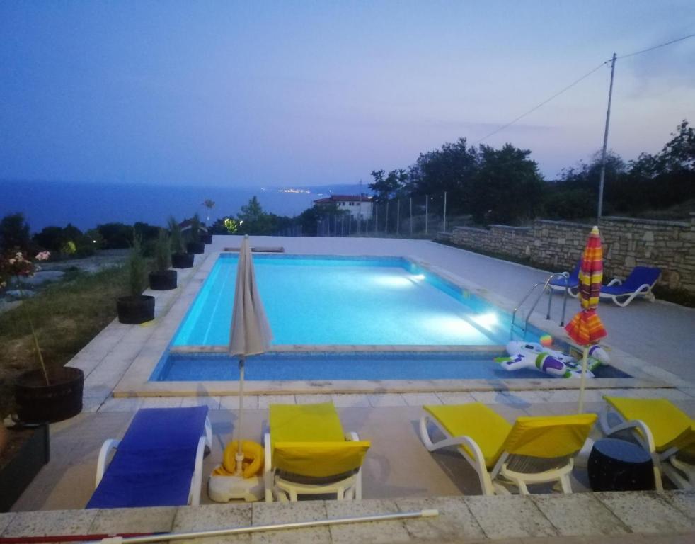 una piscina con sillas y sombrilla en Апартамент с изглед към морето и външен басейн en Balchik