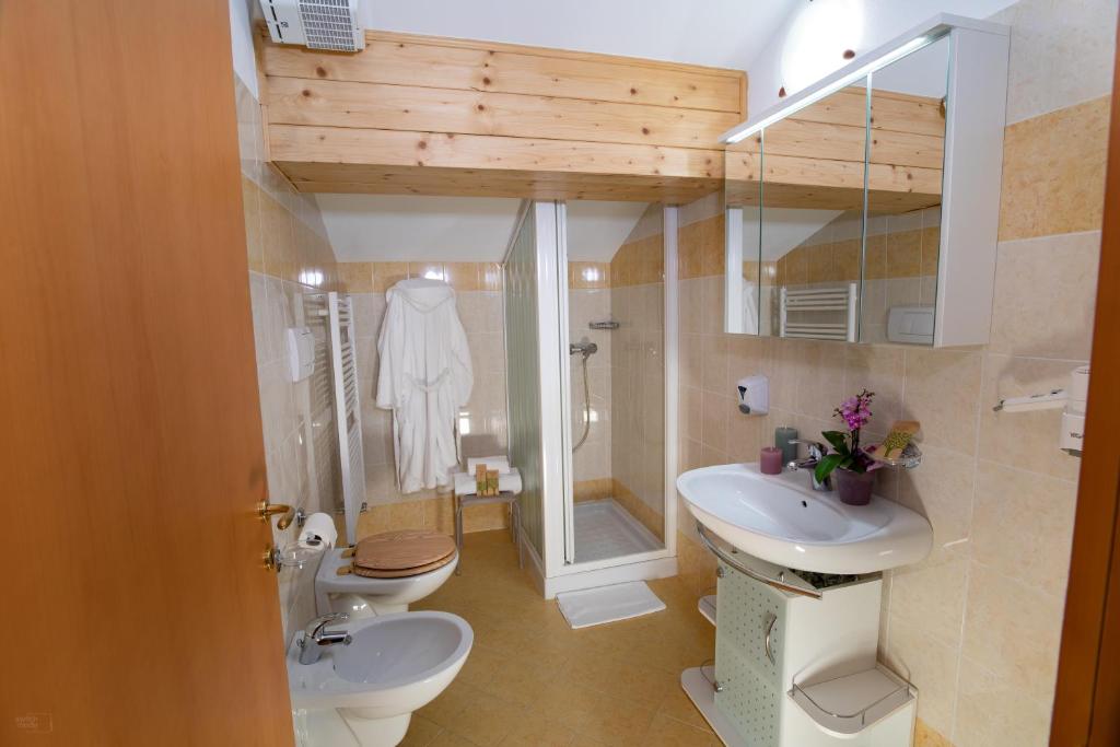 łazienka z 2 toaletami, umywalką i prysznicem w obiekcie Residence Panorama w mieście Val di Zoldo