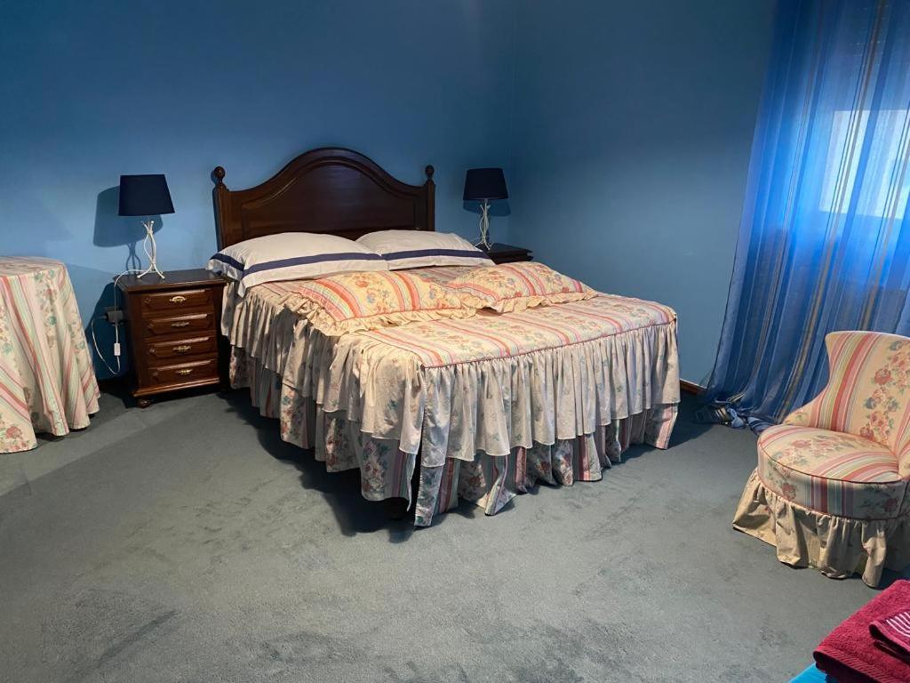 ein blaues Schlafzimmer mit einem Bett und einem Stuhl in der Unterkunft City House in Vila Real