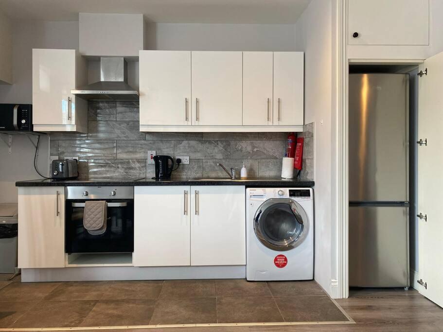 a kitchen with white cabinets and a washing machine at Lovely Studio in Dublin City Centre in Dublin