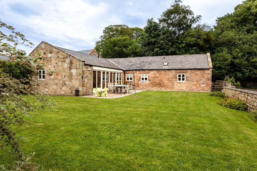 an old stone house with a large yard at Cheviot Barn in Chatton