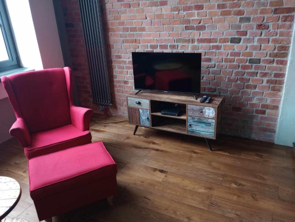 ein Wohnzimmer mit einem roten Stuhl und einem TV in der Unterkunft RedCity LOFT 129 in Żyrardów