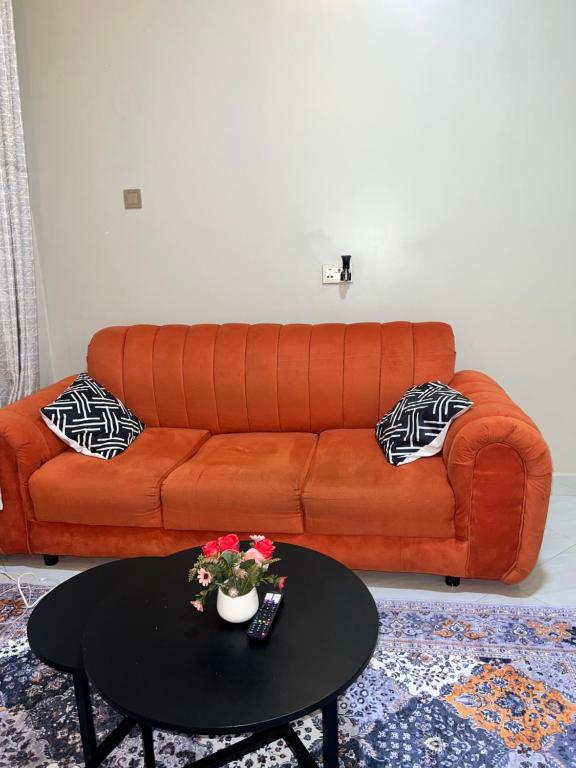 an orange couch in a living room with a table at Cozy Haven furnished apartments in Kampala