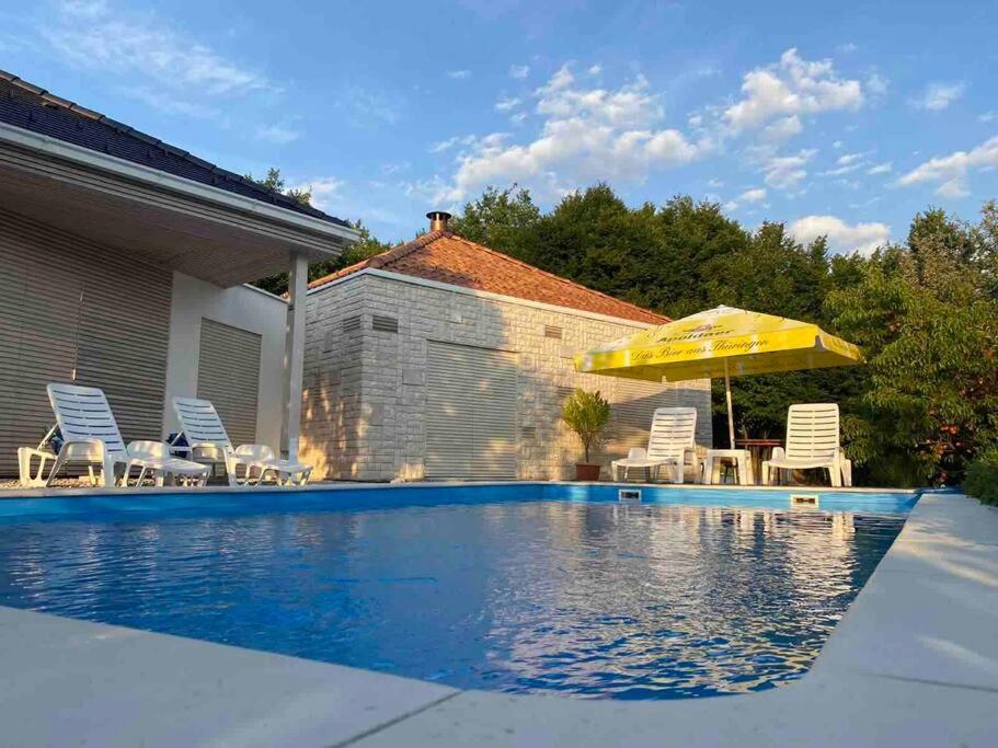 a swimming pool with chairs and an umbrella at Woodrock Villa in Sarajevo
