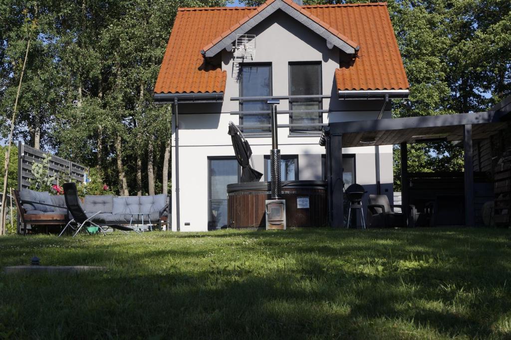 a small white house with an orange roof at Nad Dadajem Domki do Wynajęcia in Biskupiec