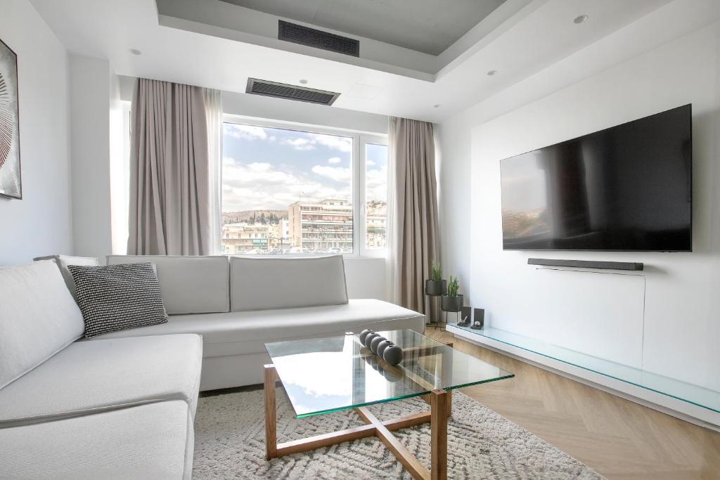 ein Wohnzimmer mit einem weißen Sofa und einem Flachbild-TV in der Unterkunft Kallirrois 89 Suite in Athen