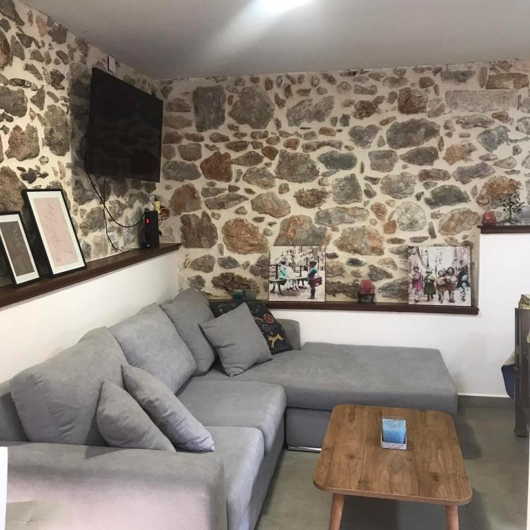 a living room with a couch and a stone wall at METAXIAS HOUSE in Leonidio