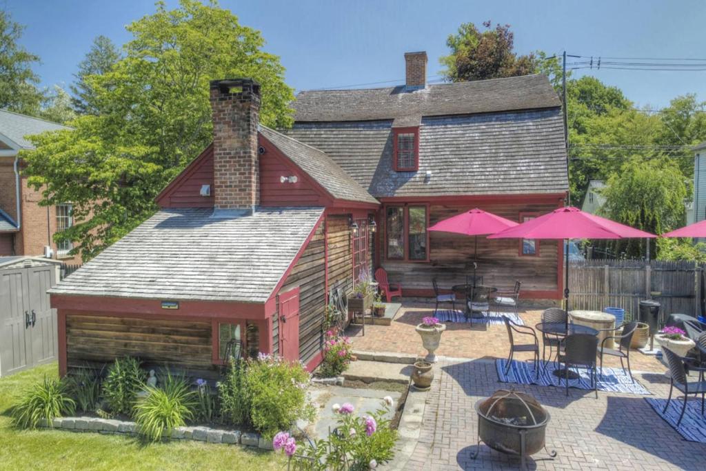 Casa con patio con mesas y sombrillas rosas en Last House on the River, en Stonington